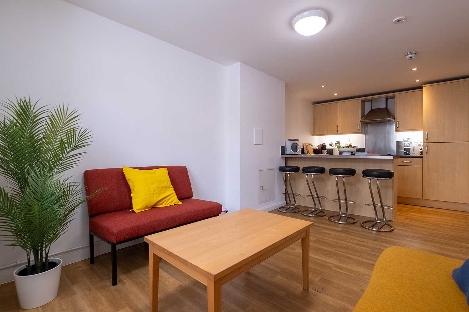 A small kitchen area with a communal seating area on one side of the room