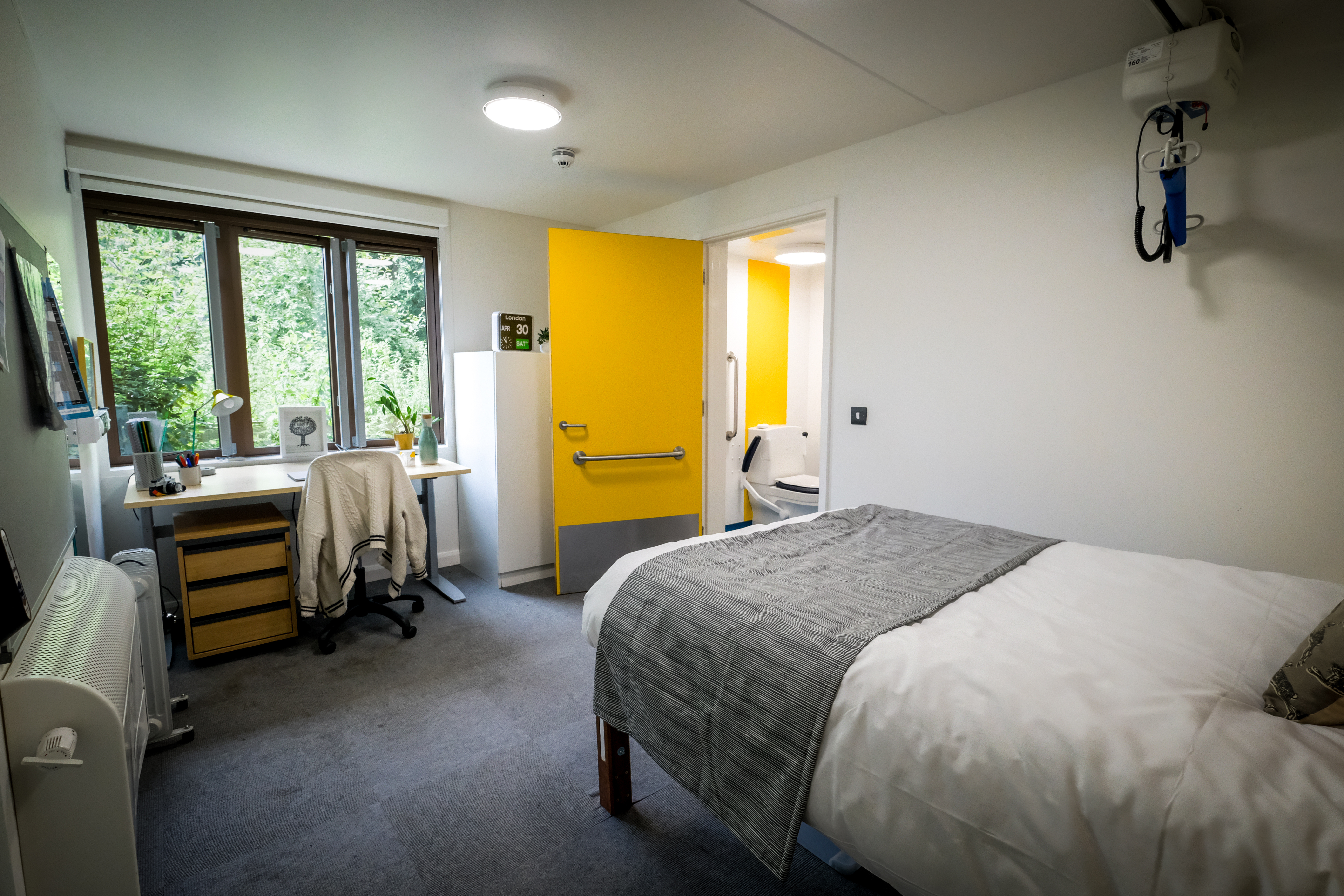 A large bedroom equipped with a hoist above the bed and grab rails on the doors