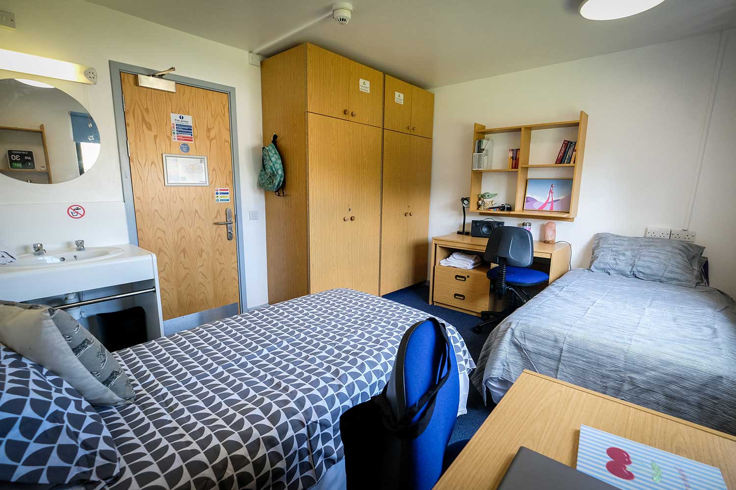 A bedroom with two twin beds, two wardrobes, two desks and a sink