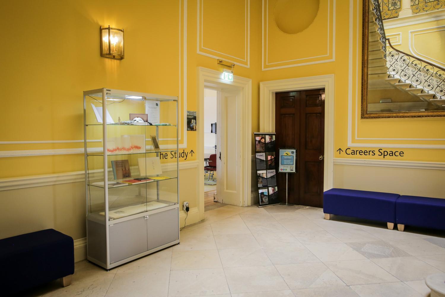 A hallway painted yellow, with period features and dark wooden doors