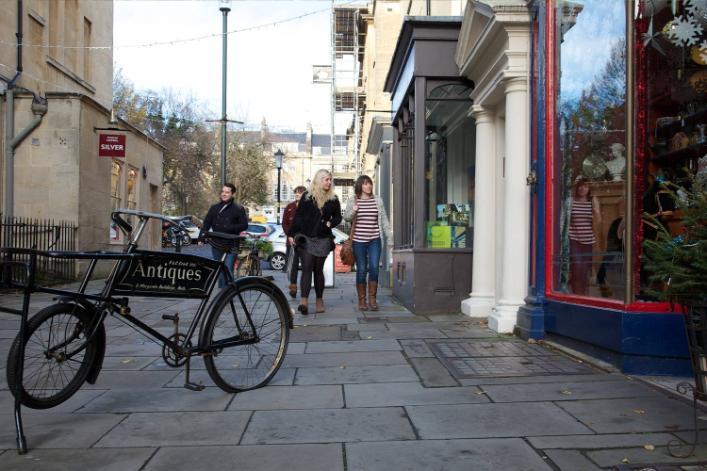 Two women walking along a shopping street. Bike with sign for antiques in foreground