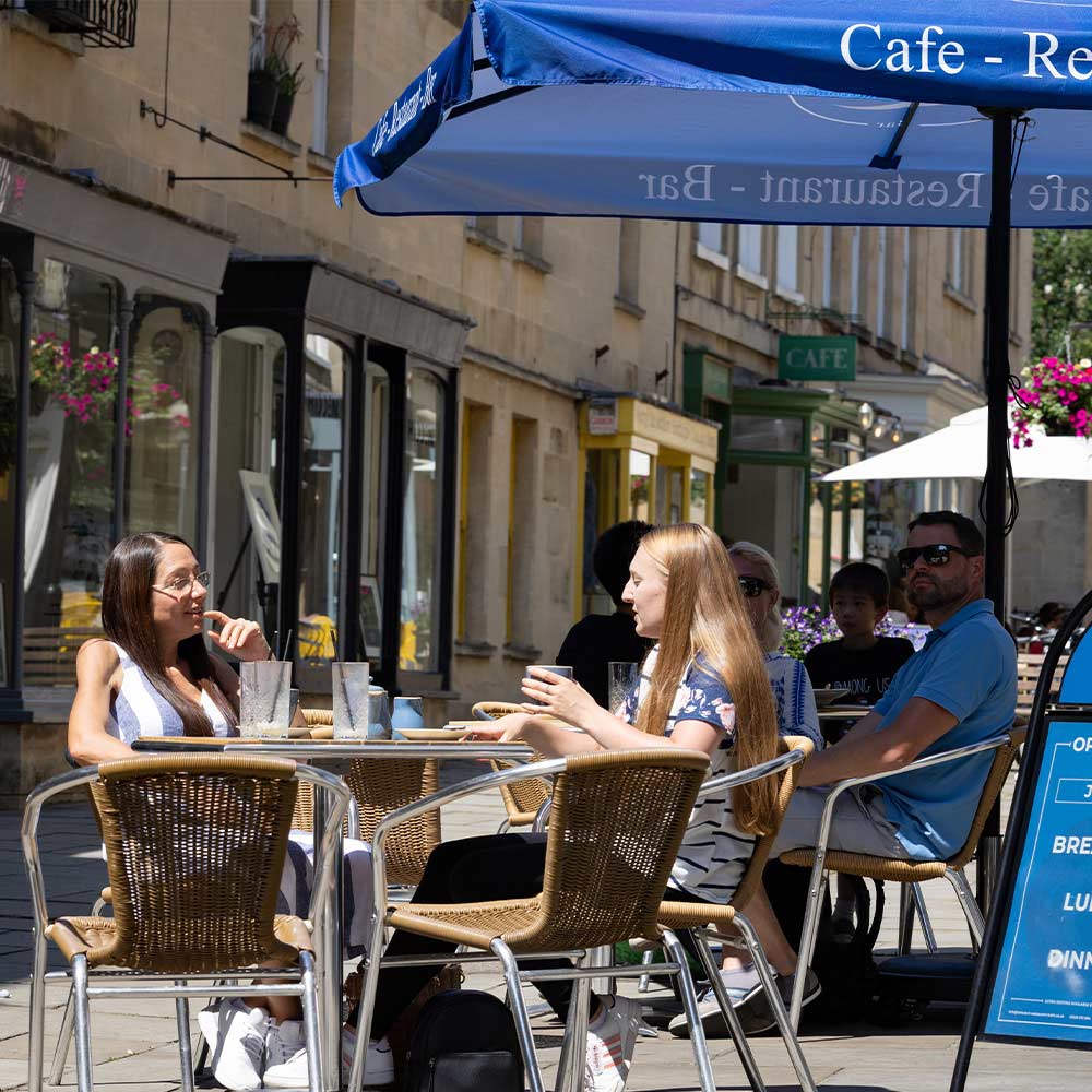 Pair of students sitting outside a cafe in sunshine