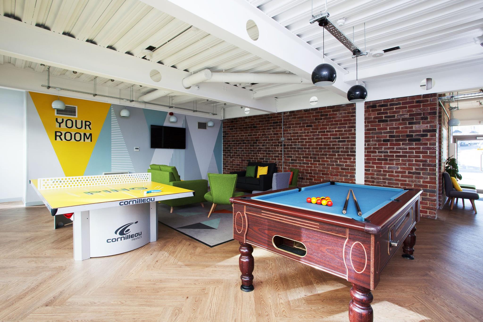 A communal seating area, pool table and table tennis table in an open-plan room