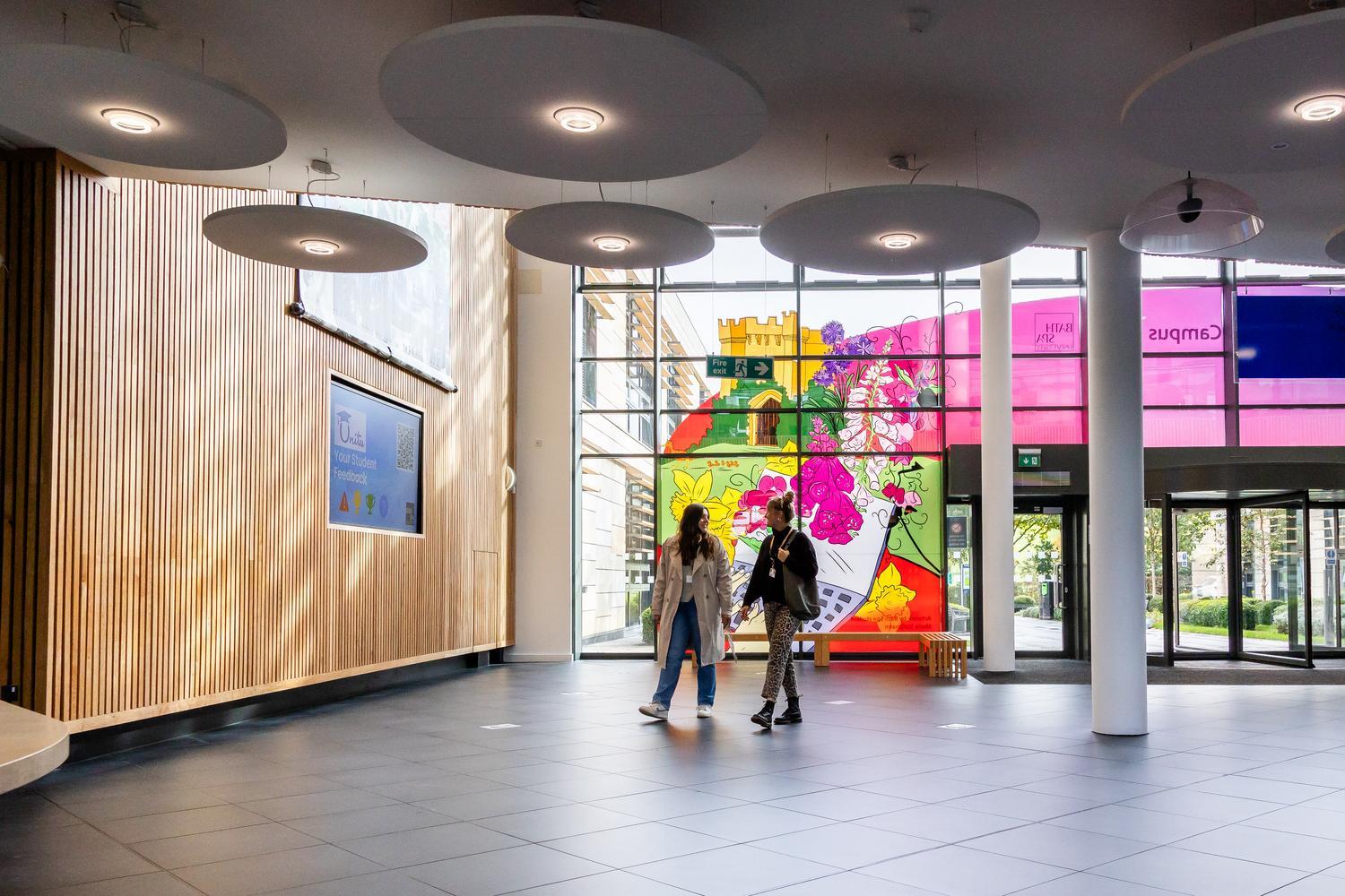 Two students walk across a spacious entrance hall