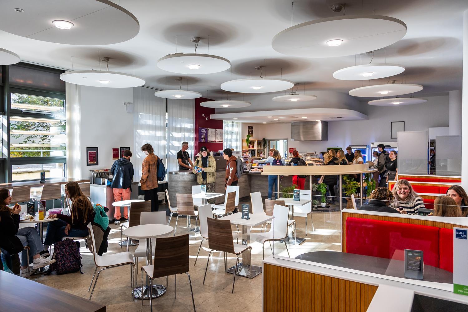 A busy cafe with students standing to place an order and sitting at a tables