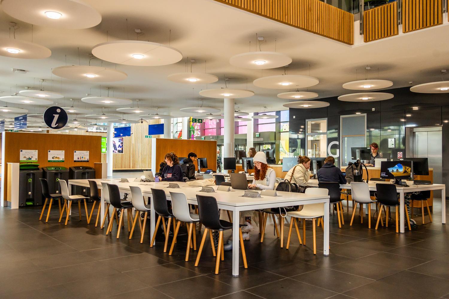 Large tables surrounded by chairs, with computers on some desks