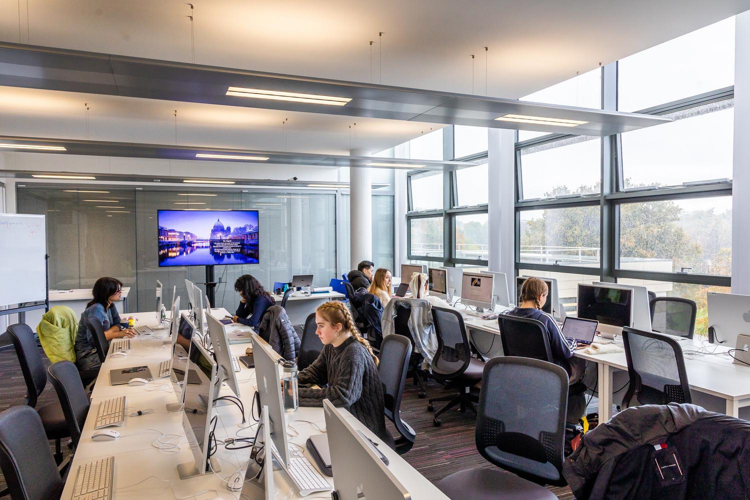 A large computer suite with large glass windows and students sitting at desks