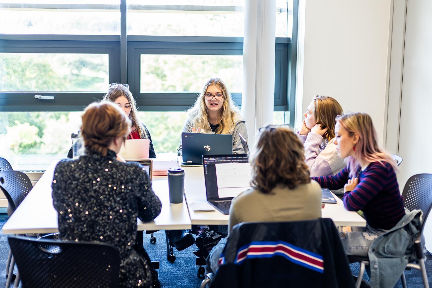 Six students sitting around a table in a seminar room