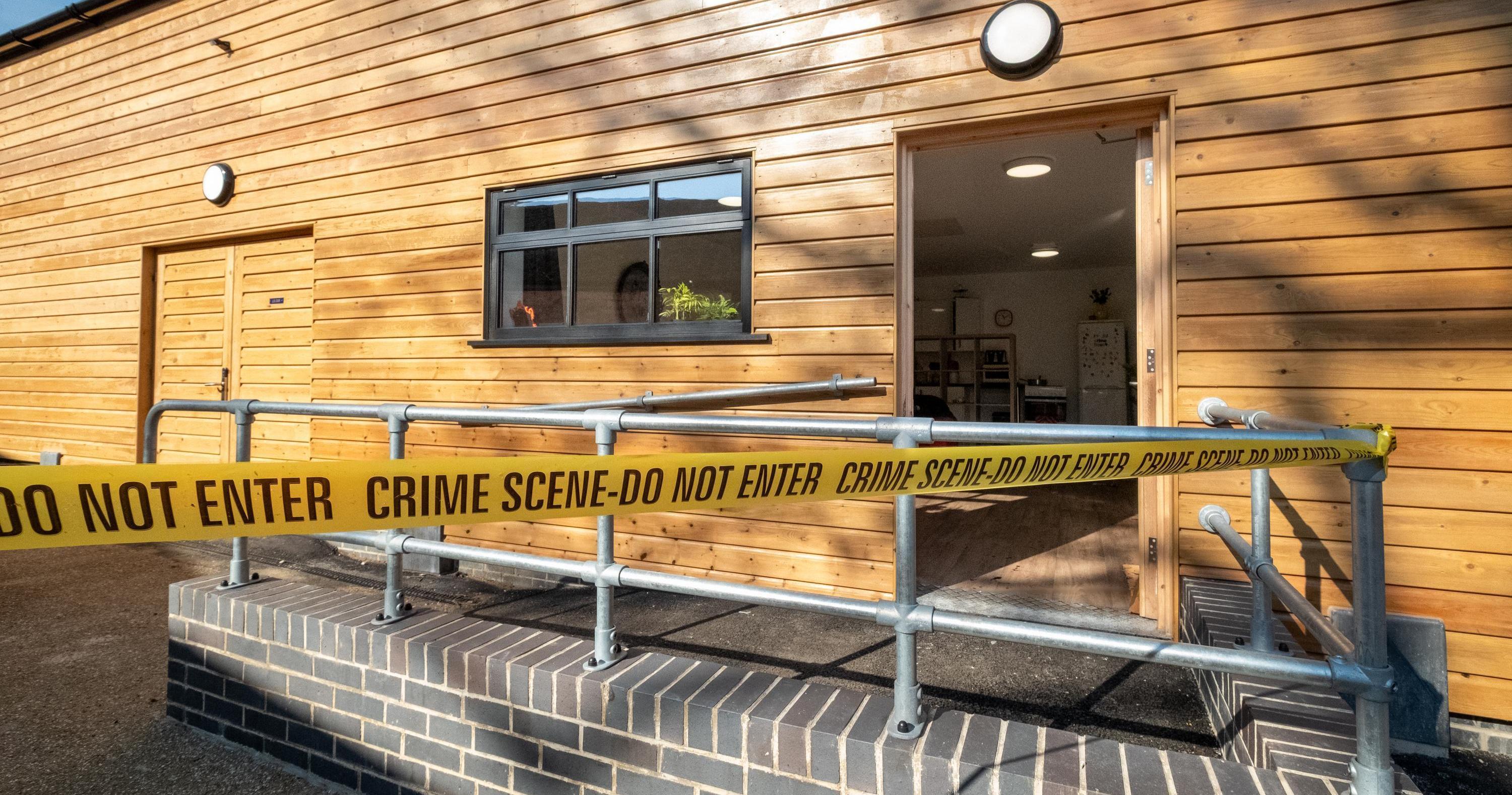 A wooden clad building with yellow crime scene tape around it