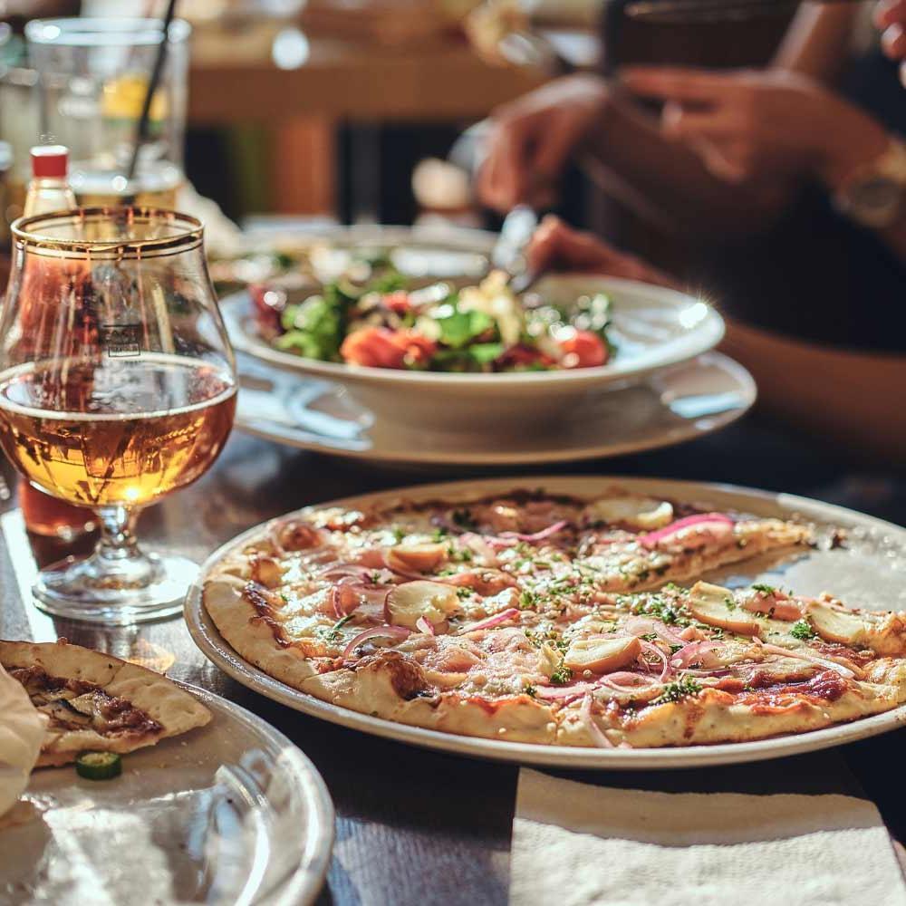 Young friends students eat pizza and salads in a cafe