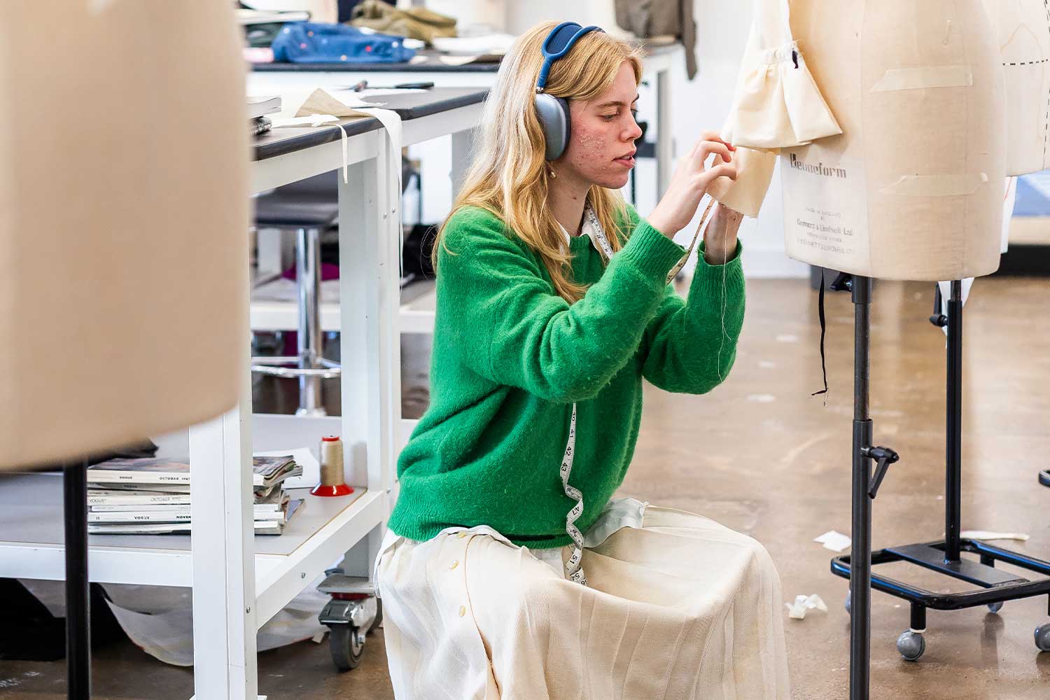 A student pins fabric on to a mannequin