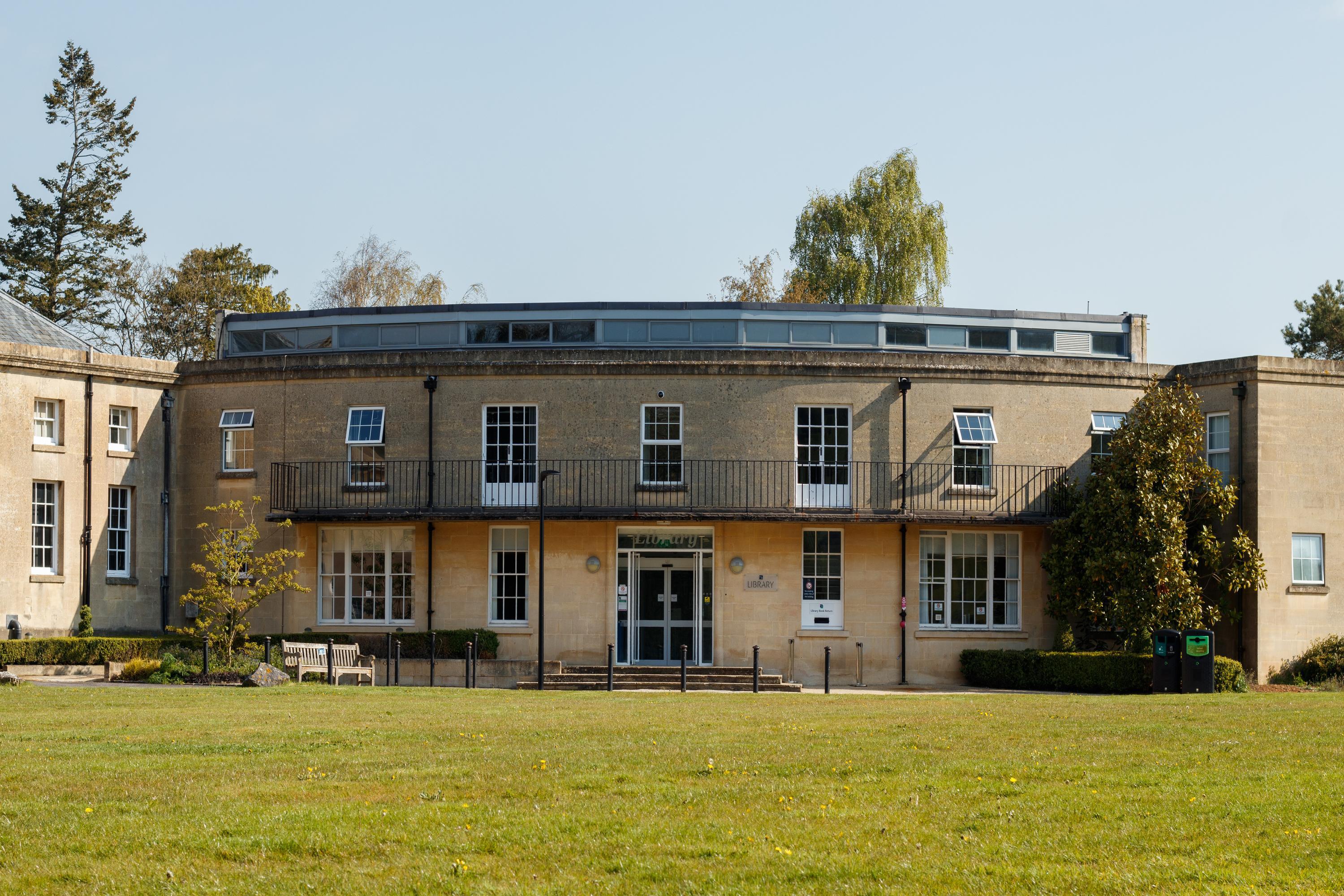 A two-storey stone building with a large green lawn at the front
