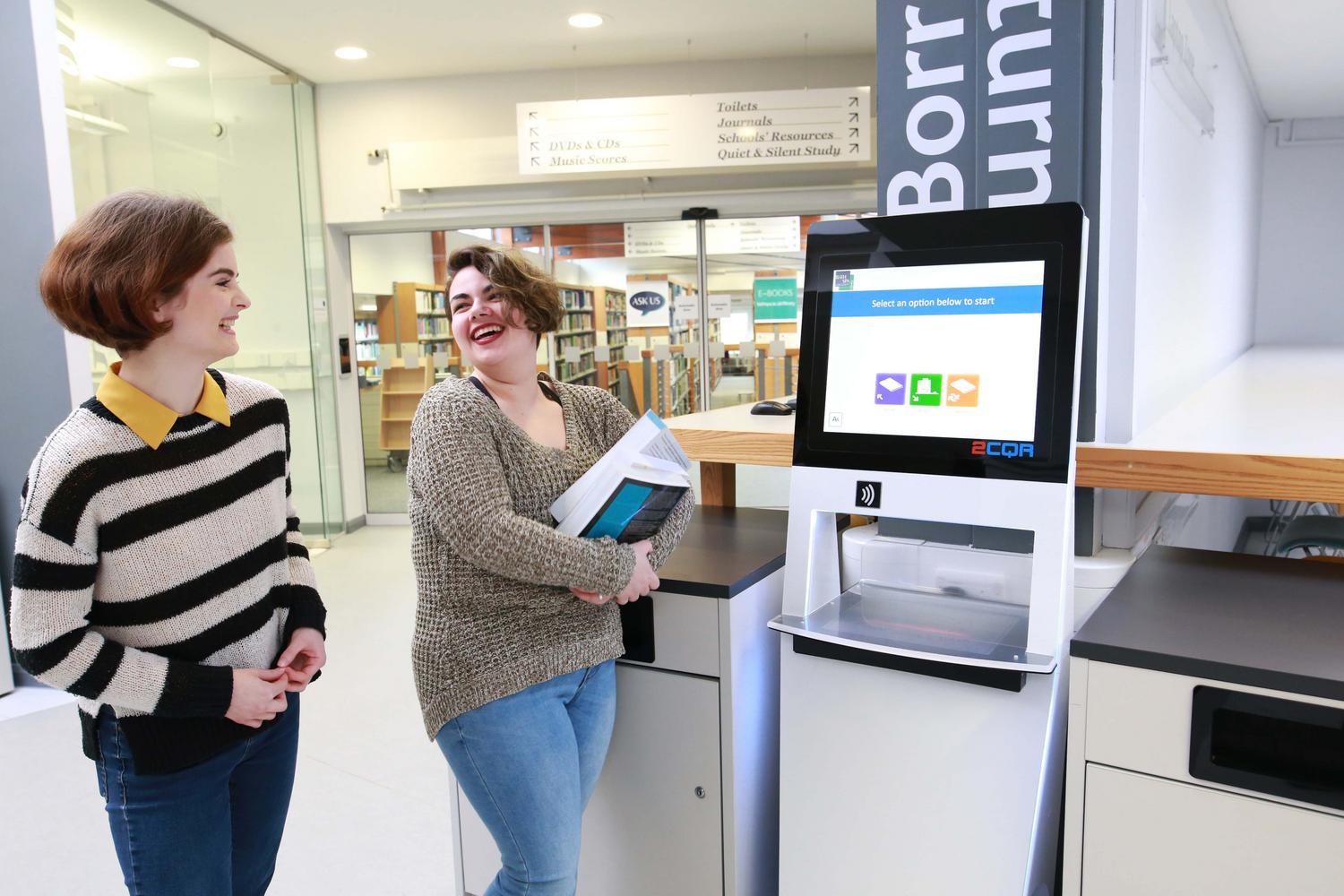 Two people walk to machine to return library books