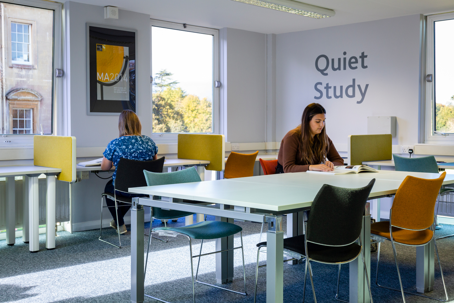 A quiet study space in the library, with desks and chairs arranged around the edge of the room
