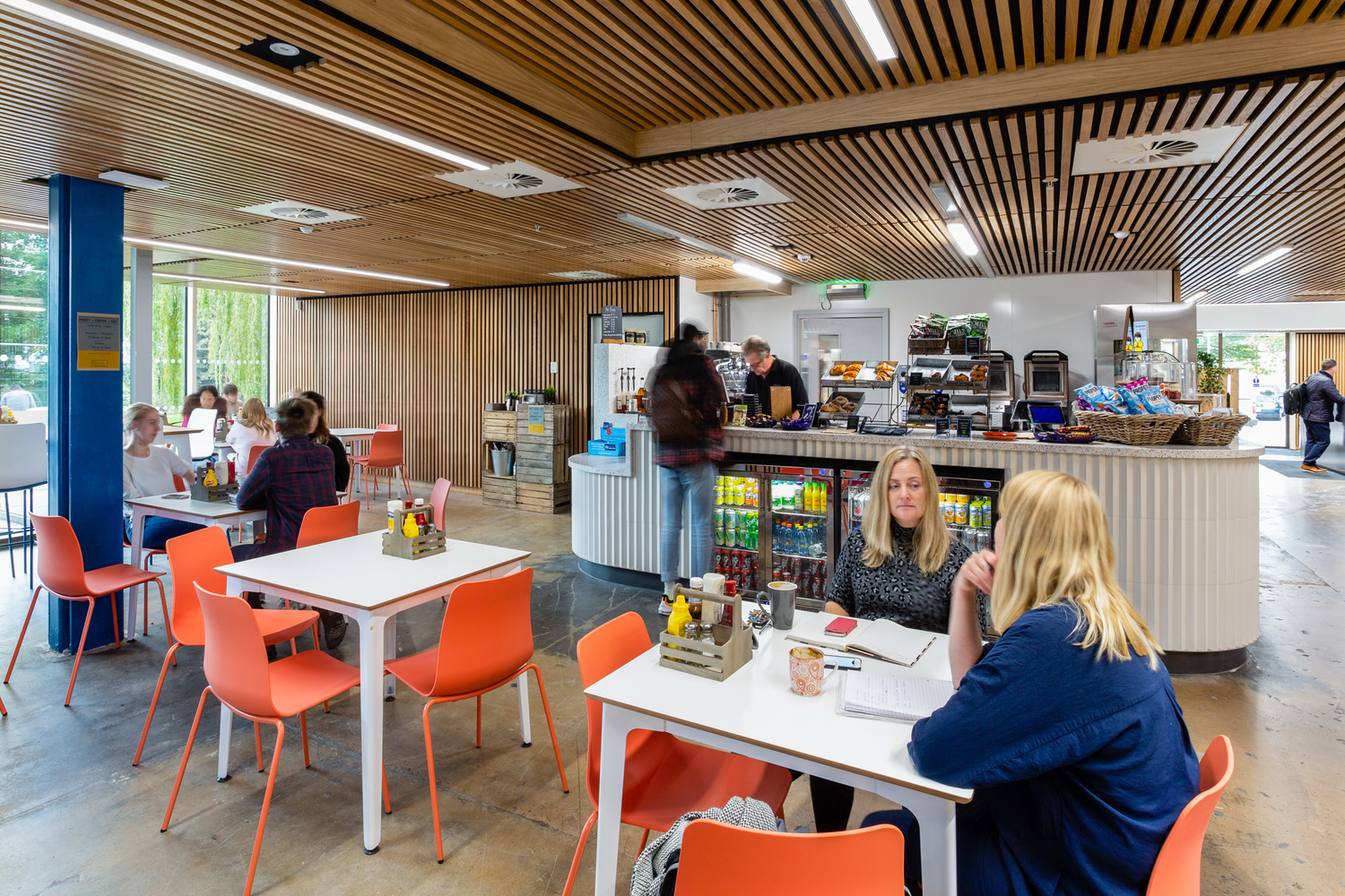 A colourful cafe with one person ordering and others sitting at tables