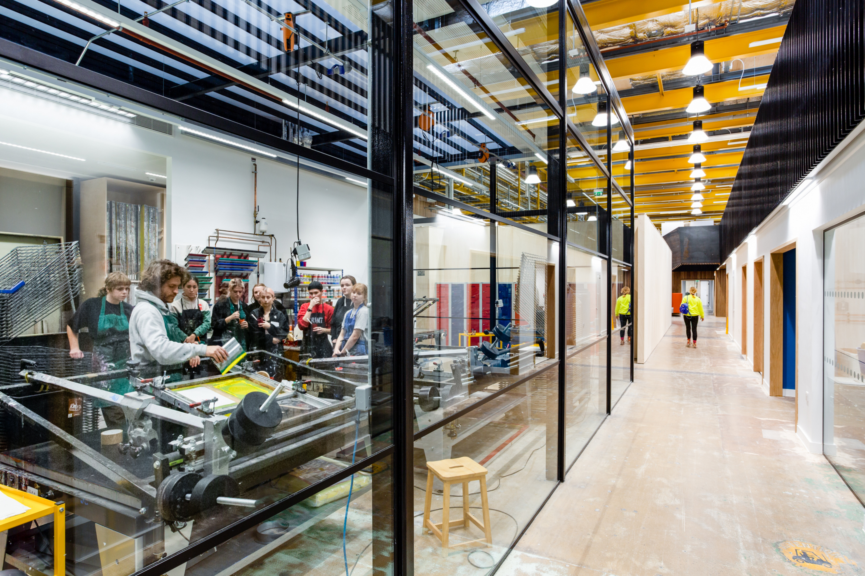 An empty corridor with large glass windows that look into a screenprinting workshop