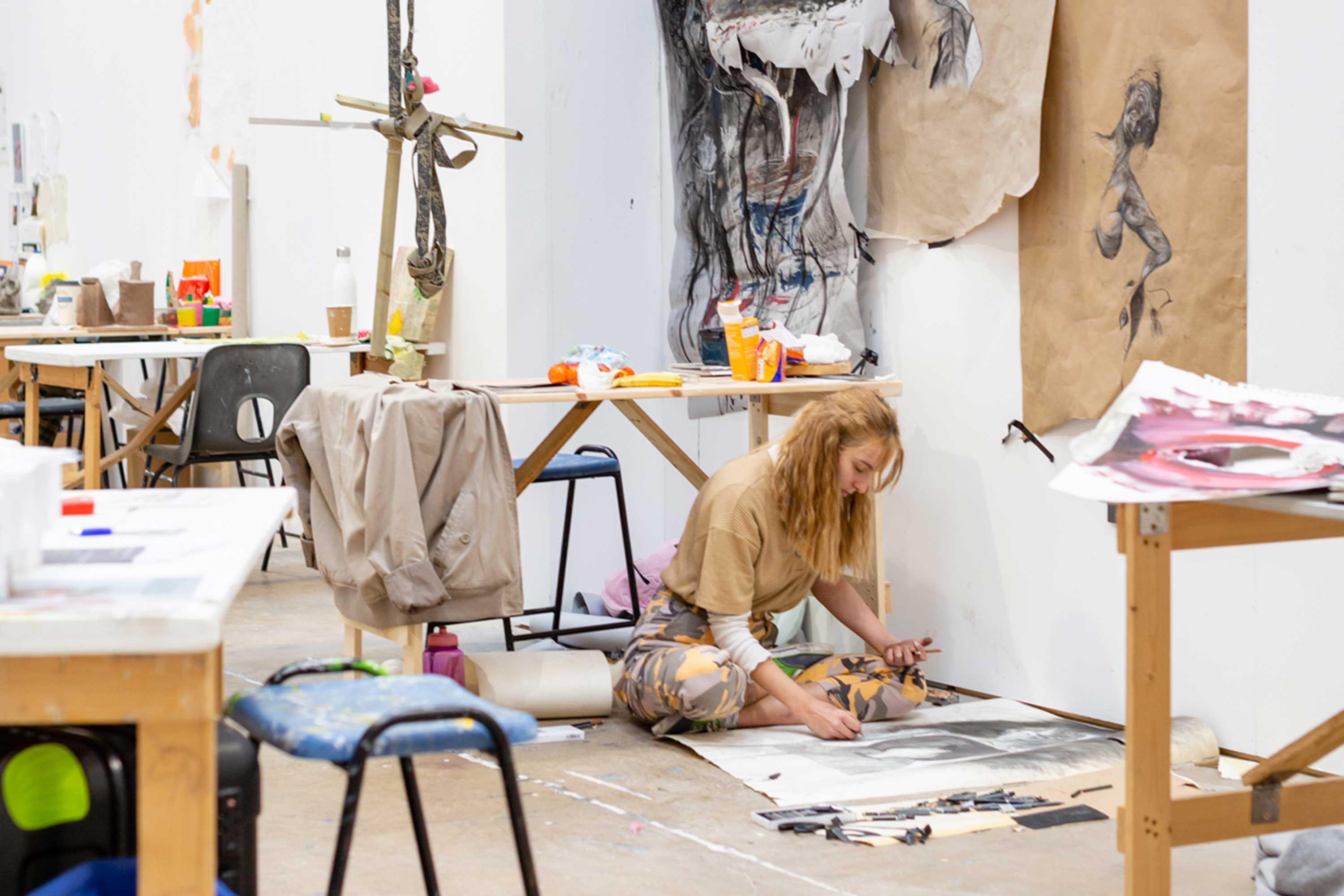 A student sits on the floor in the artists