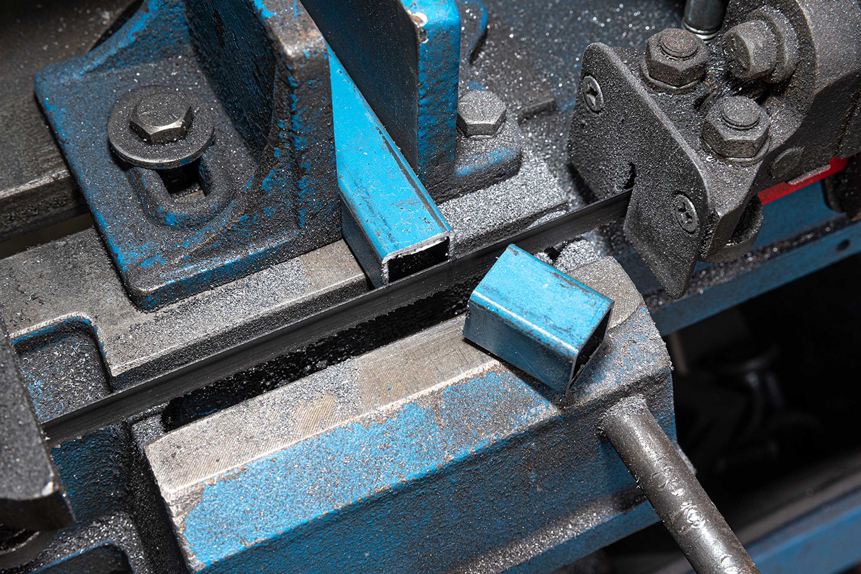 A close up of a metal tube being cut in half by machinery