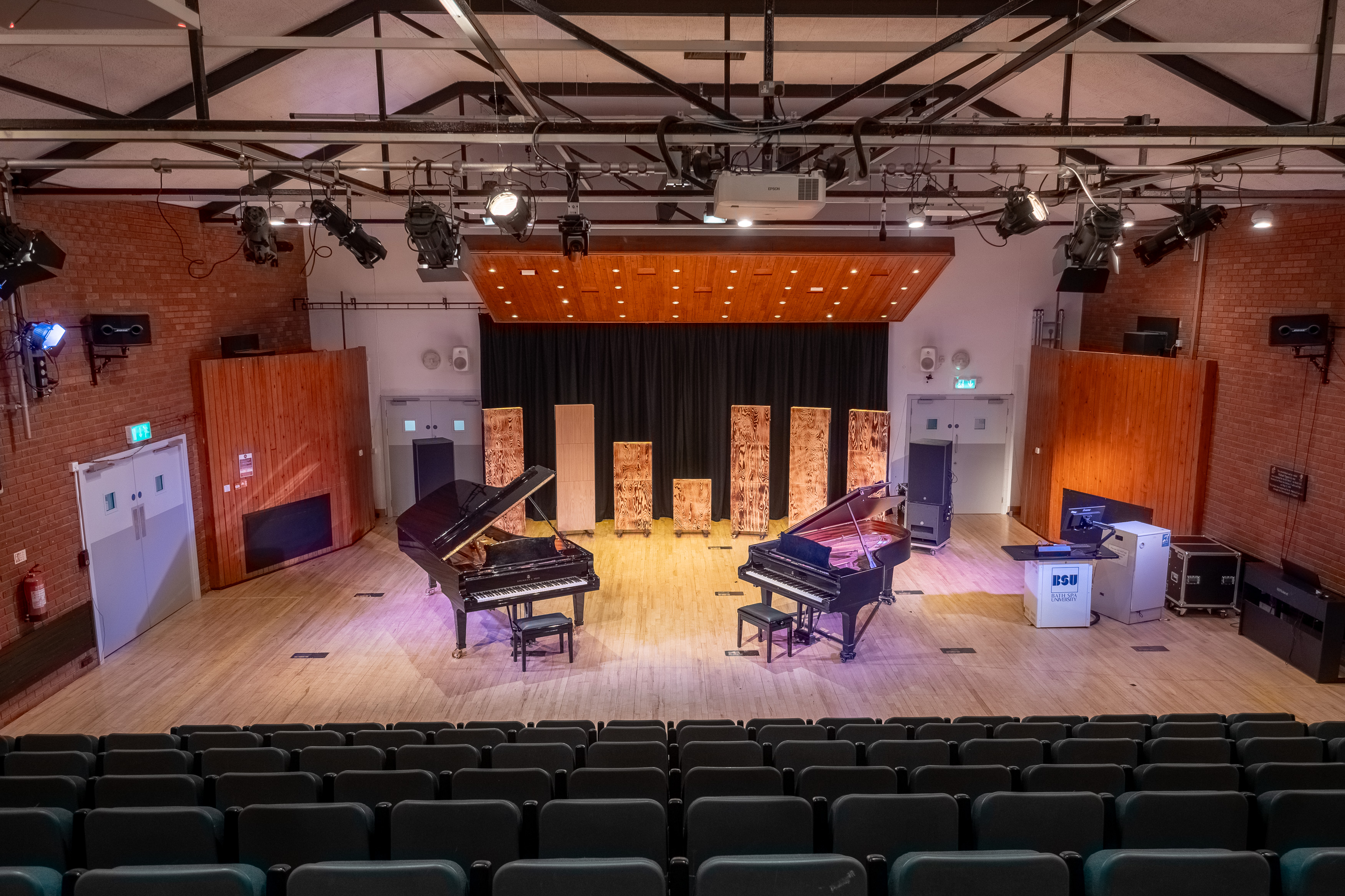 A stage with two grand pianos at the front