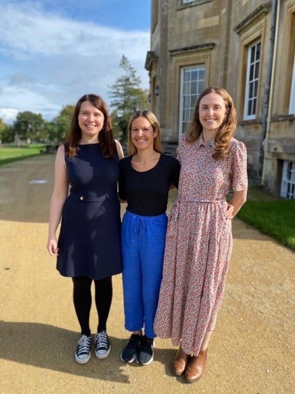Three members of the Outreach Team stand behind Main House