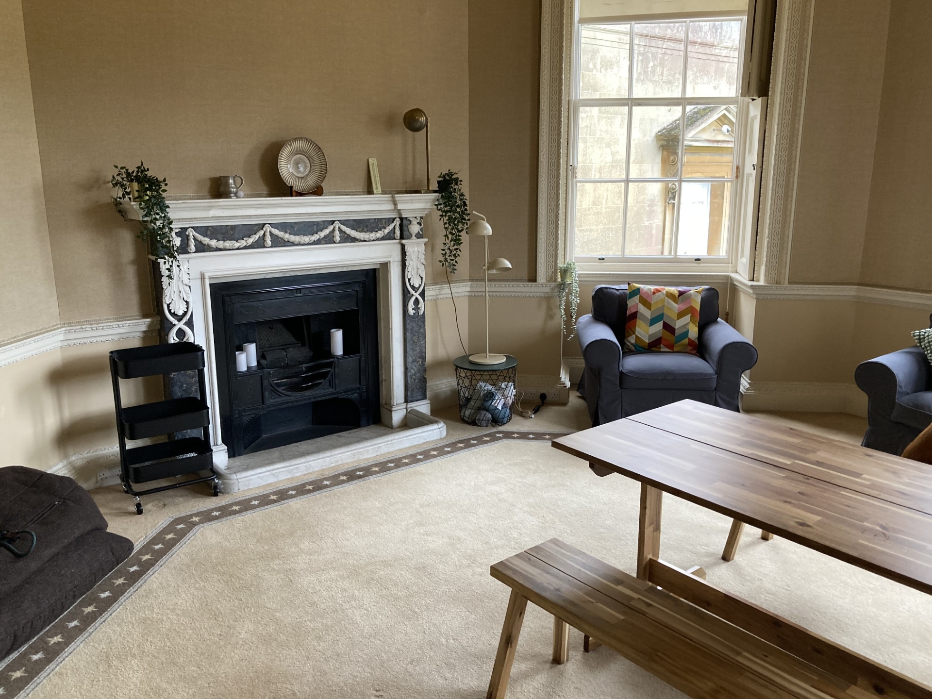 A cosy sitting room with a large fireplace, armchair and dining table