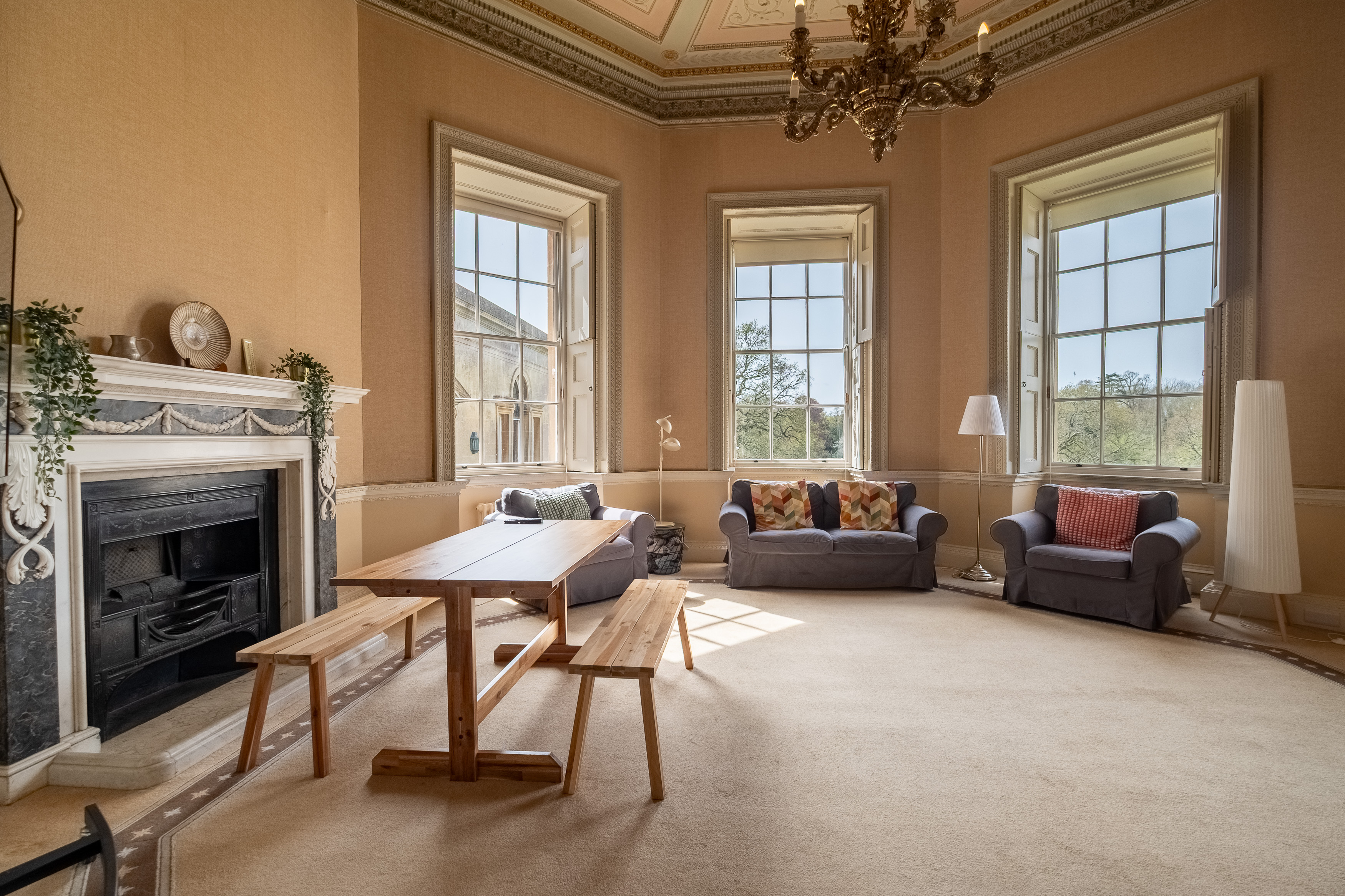 A cosy sitting room with a large fireplace, armchair and dining table