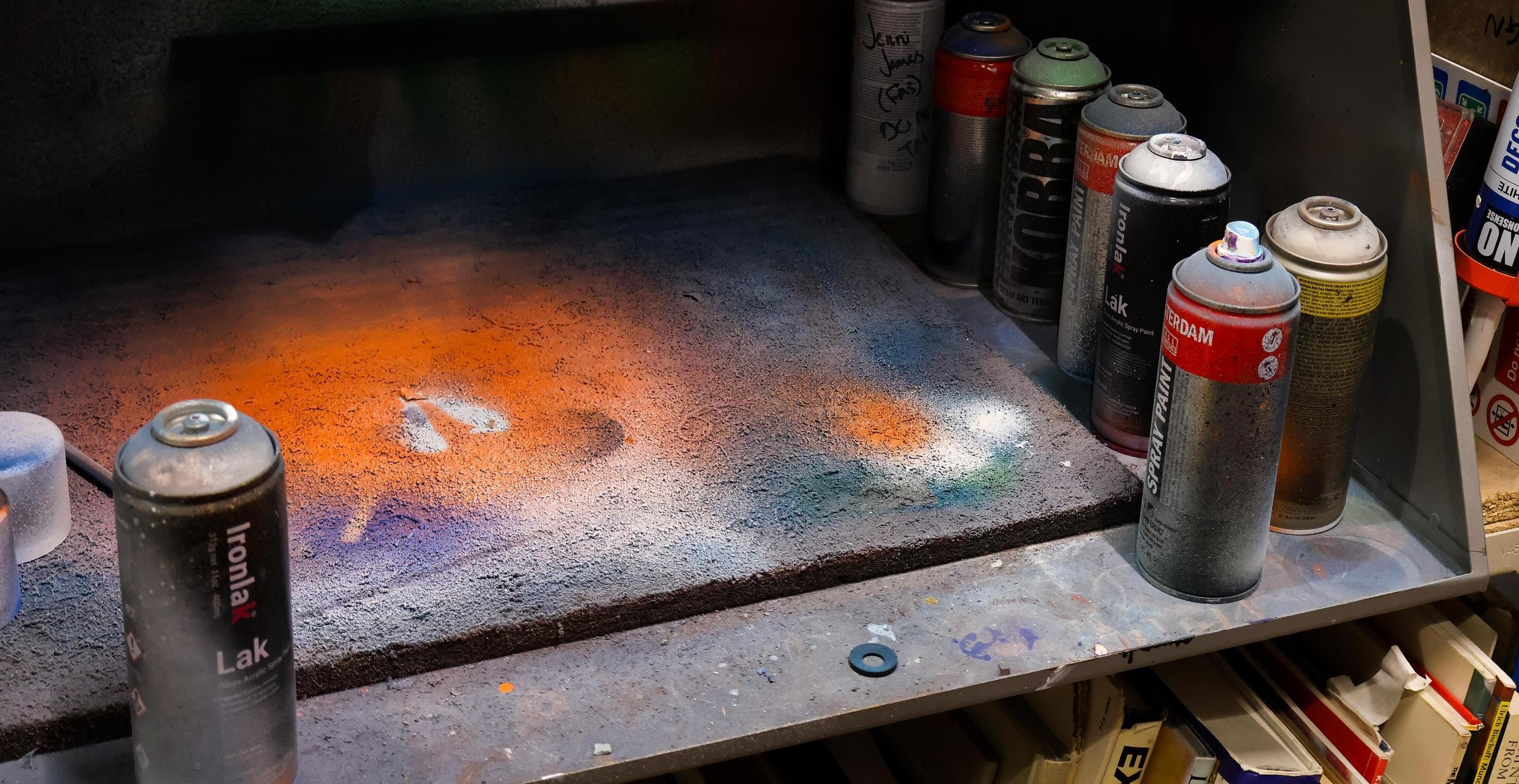 Cans of spray paint around a large open space for spraying