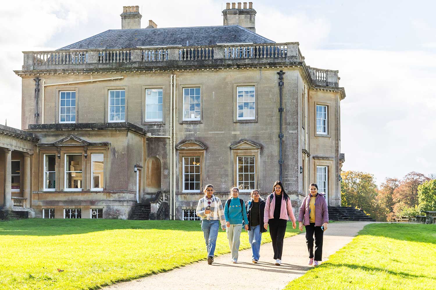 A group of five students walking past main house