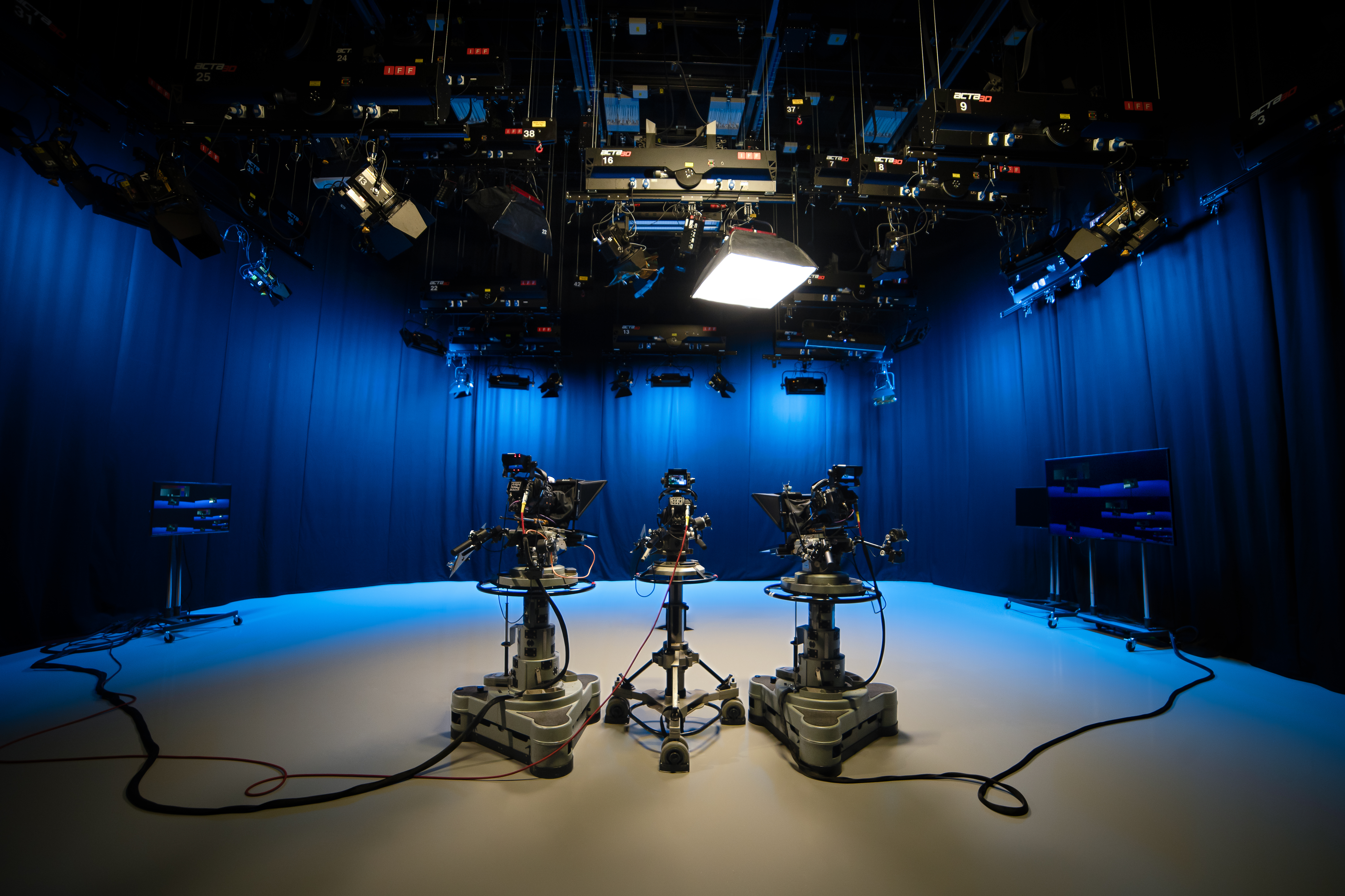 An empty TV studio with three large camera and blue lighting