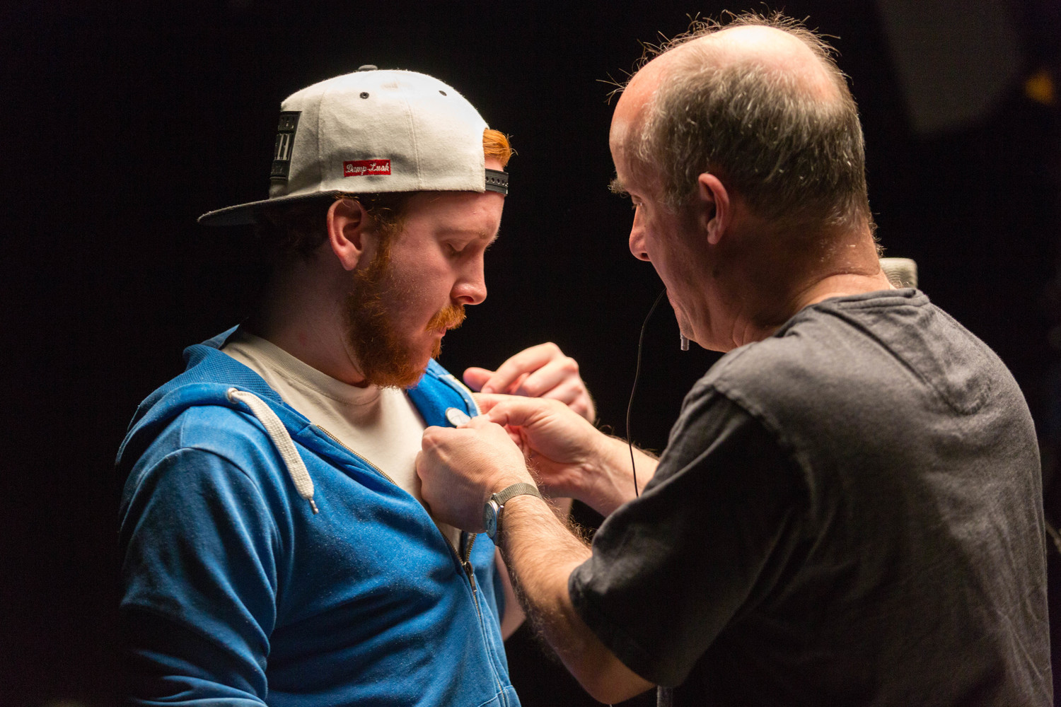 A person fitting a microphone to another person