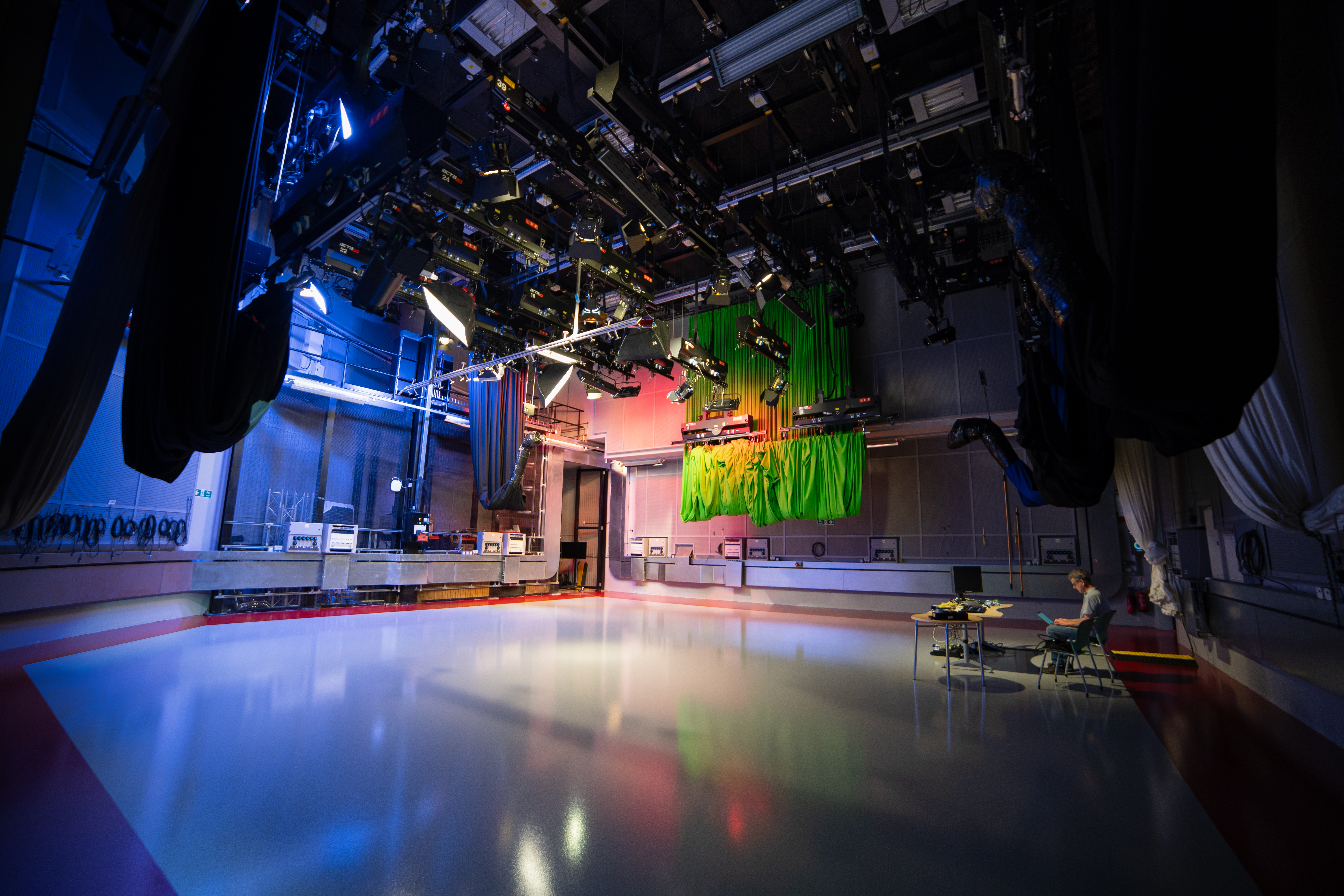 An empty TV studio with one person sitting in the director