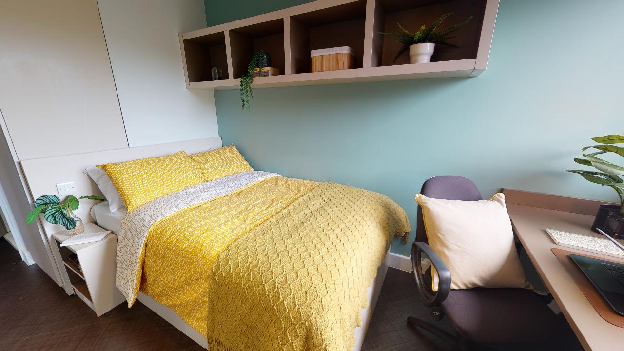 A student bedroom with a bed, desk and chair