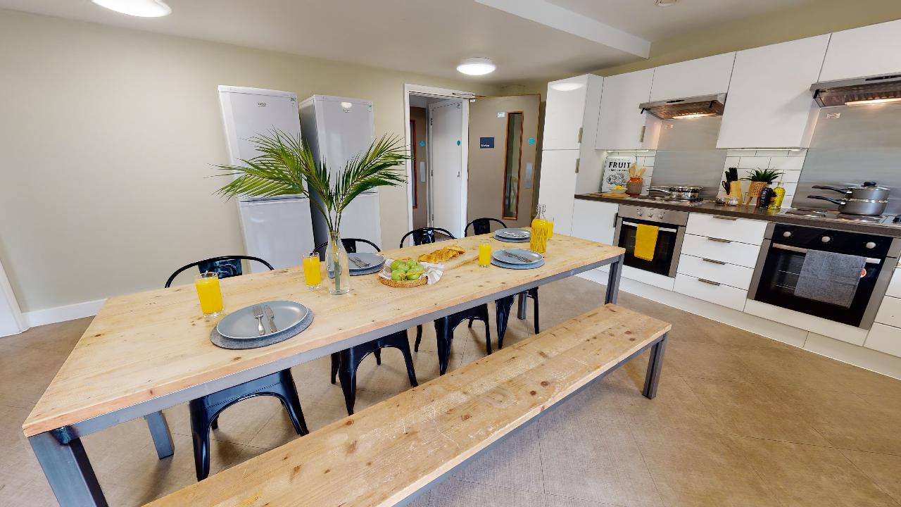 A large kitchen with one long dining table in the centre