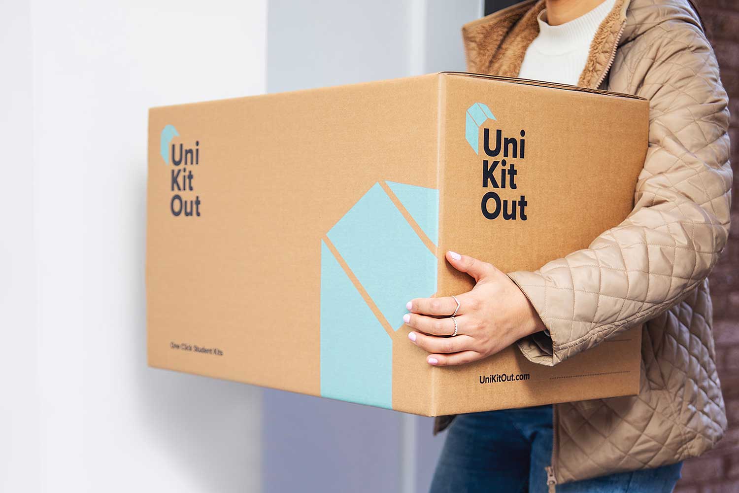 A person carrying a large cardboard box with UniKitOut branding on it
