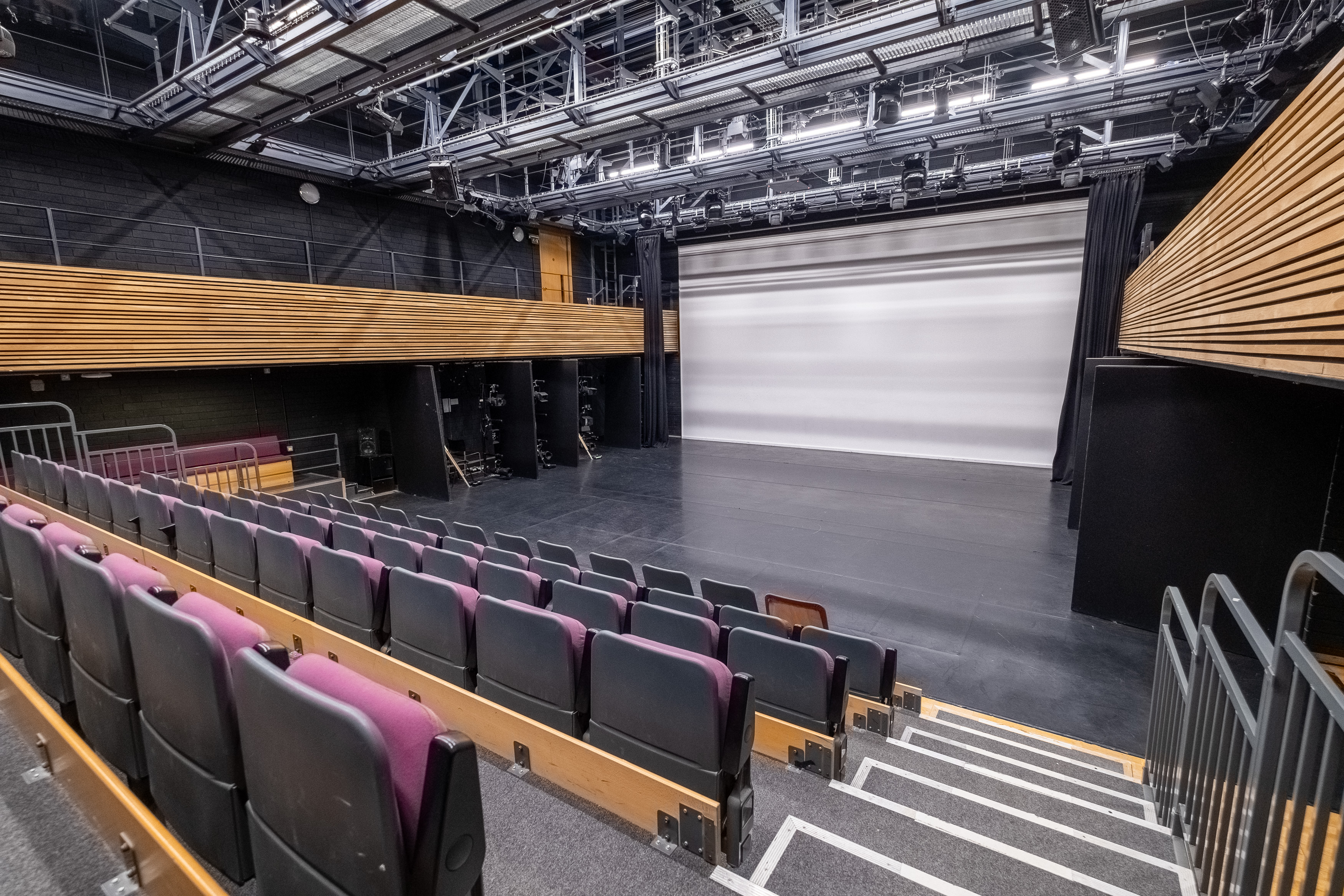 An empty theatre with black walls and tiered seating
