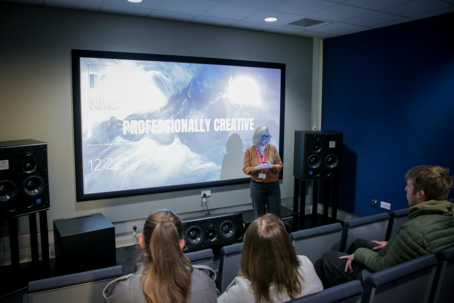 A cinema-like room with a large screen, speakers and seating