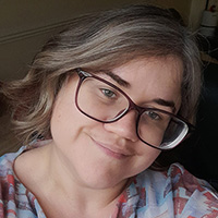 A student smiling against a dark background.