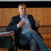 A student sitting on a chair in a wood-panelled room.
