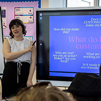 A Bath Spa University student stands presenting next to a screen.