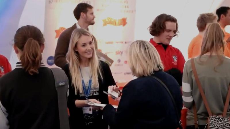 Woman hands business card to an interested visitor