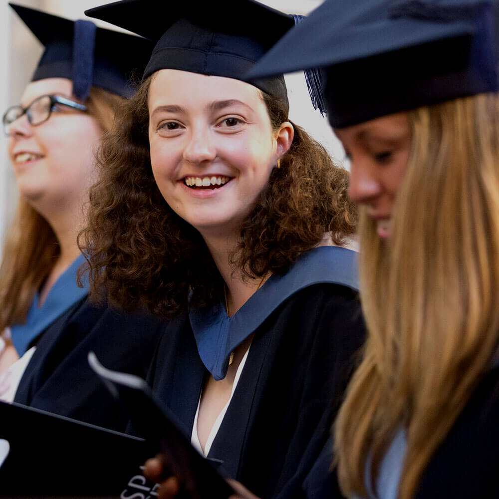 Smiling student in cap and gown attending her graduation ceremony