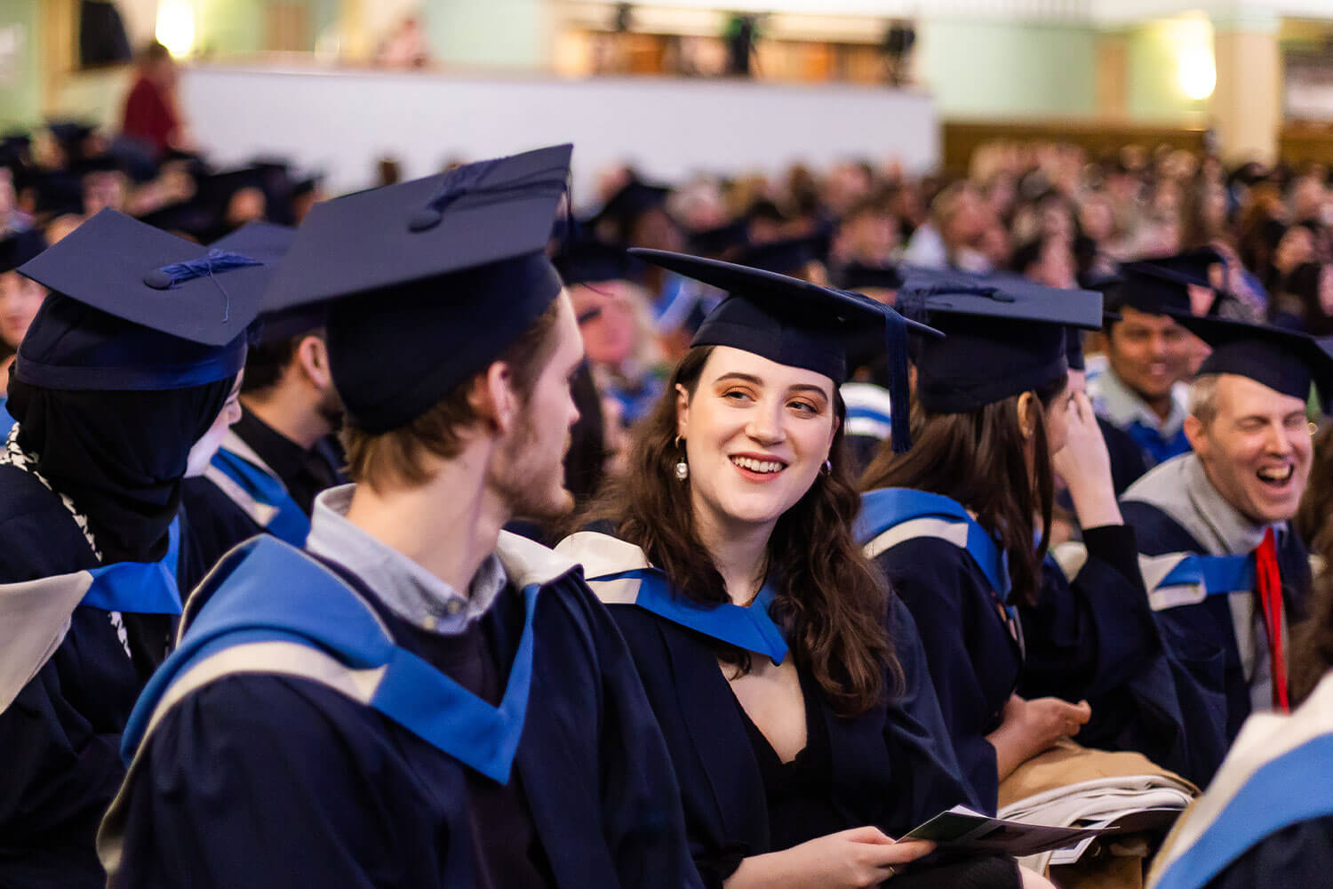 Graduands talking together in the audience at their graduation ceremony