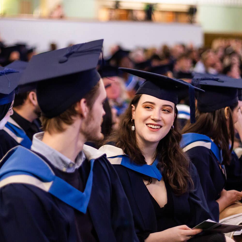 people in a bath spa graduation ceremony audience chatting