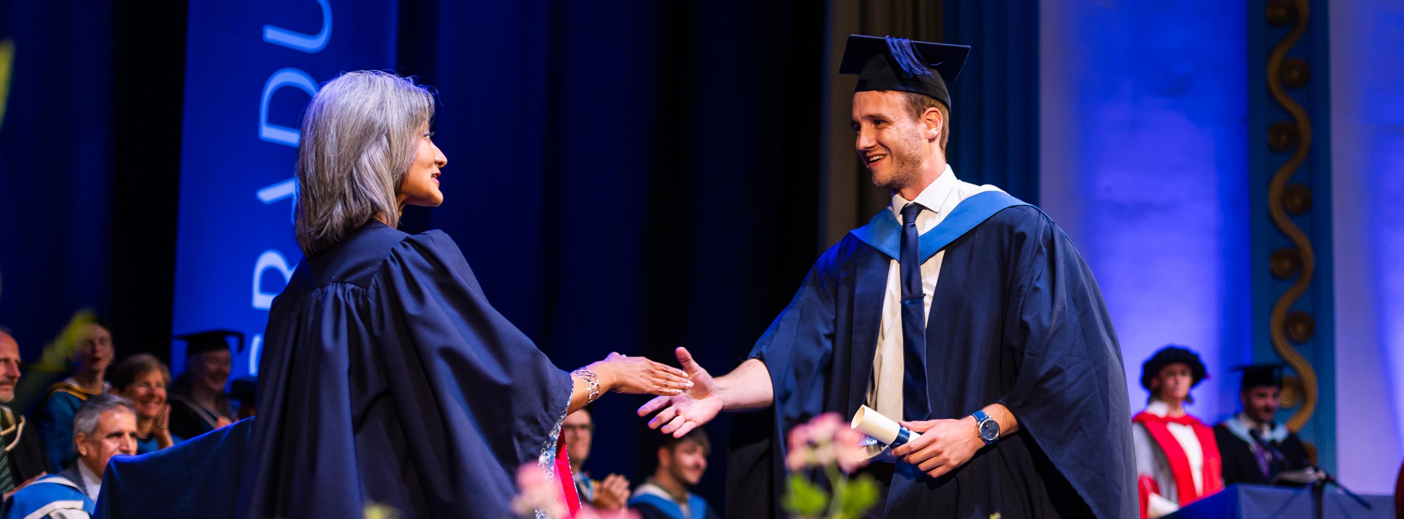 A student shakes hands with the Chancellor at Graduation