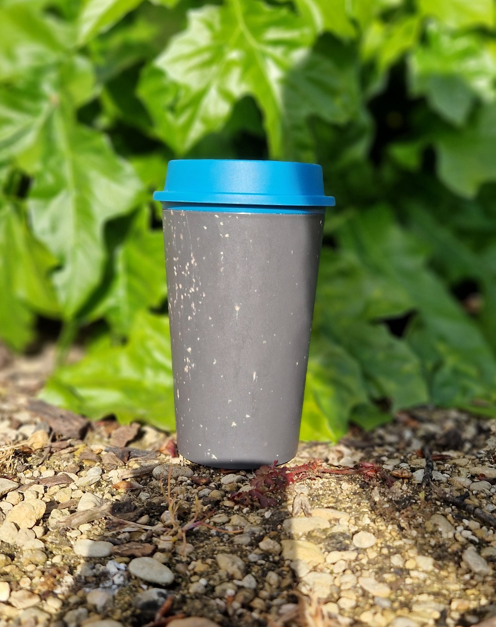 A black reusable coffee cup with a blue lid