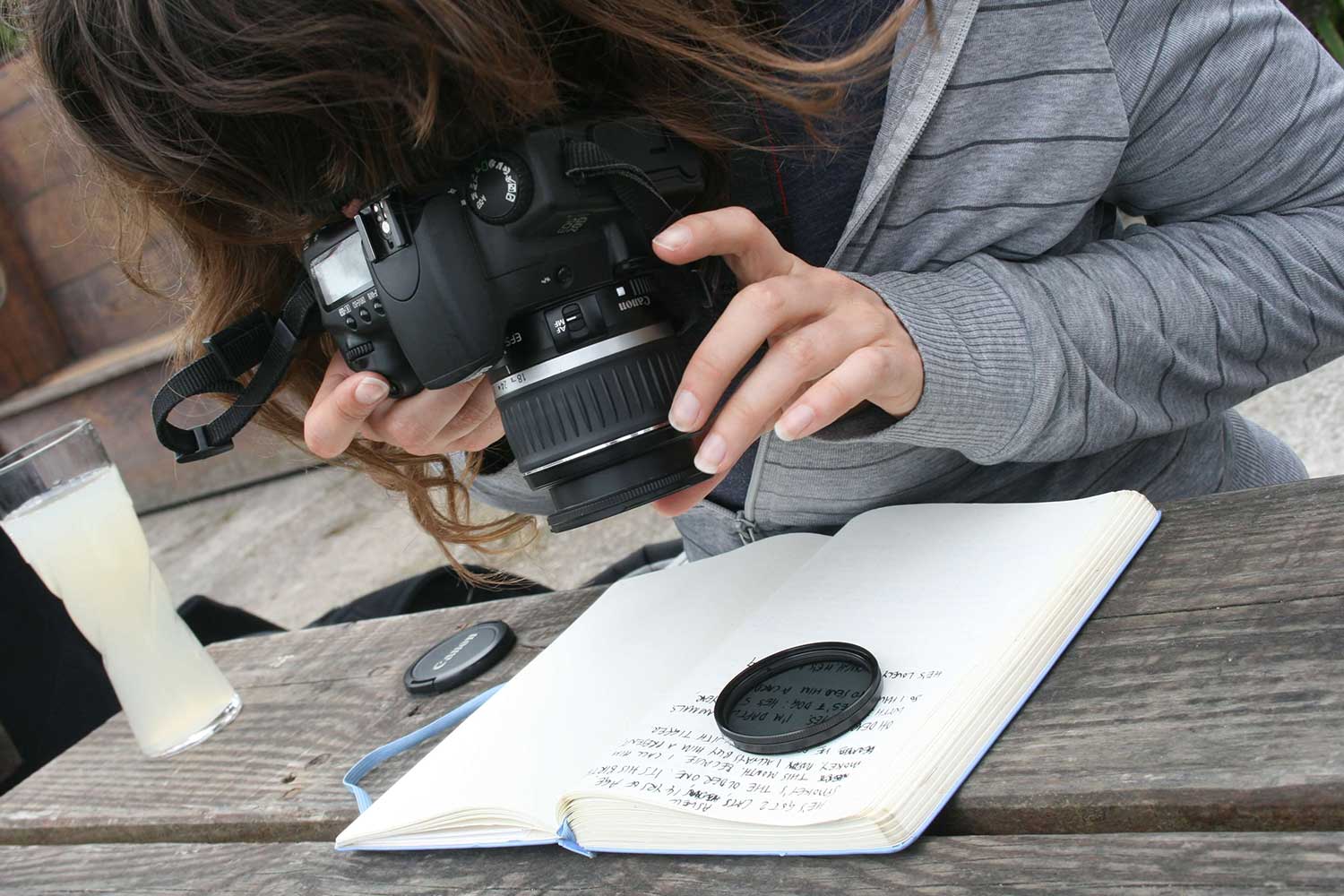 A person leans over a picnic bench to take a photo of their notes