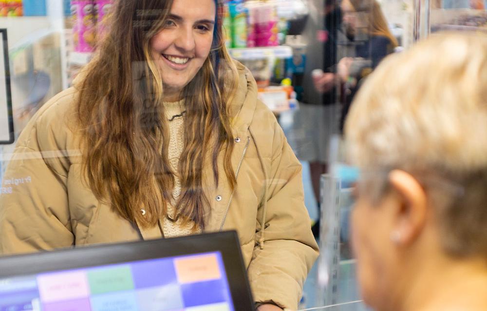 Smiling student standing at a shop counter