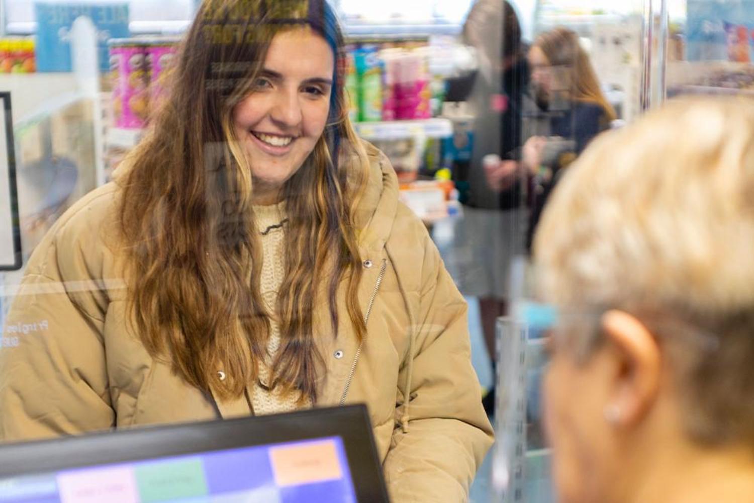Smiling student standing at a shop counter