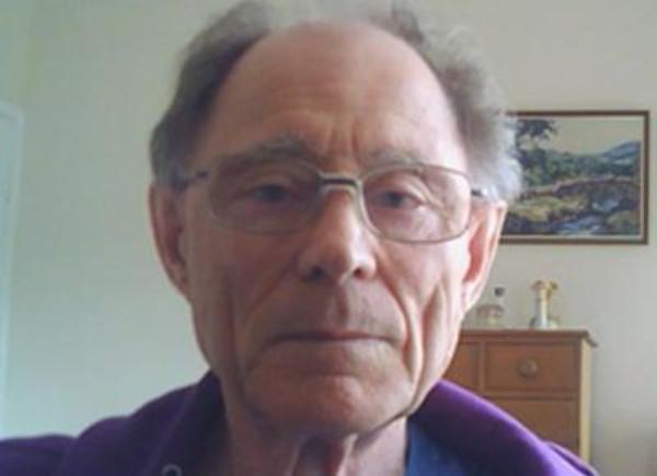 Person with grey hair wearing glasses and blue t shirt