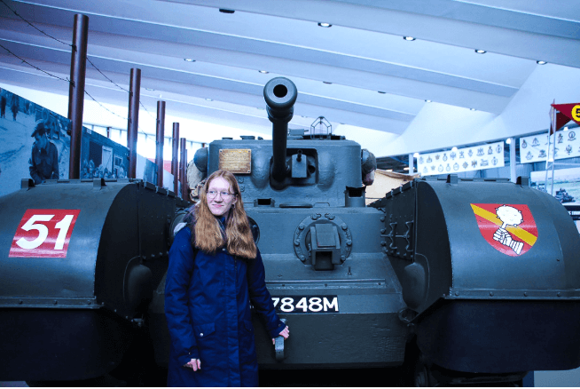 A student smiles in front of a large tank.